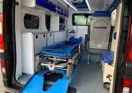Plenerowe wnętrze ambulansu przystosowanego do przewozu osób niepełnosprawnych z nowoczesnym łóżkiem medycznym i sprzętem ratunkowym.
